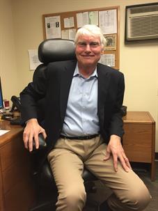 man in office chair smiles at the camera